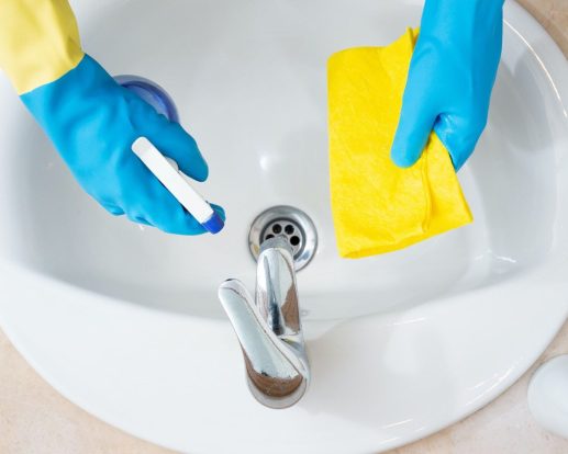 Hands with protection gloves cleaning a bathroom Hands with protection gloves cleaning a bathroom