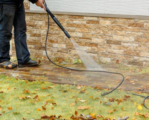 Man cleaning street with high pressure power washer, washing stone garden paths Man cleaning street with high pressure power washer, washing stone garden paths