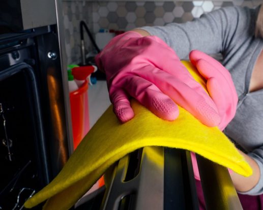 Young woman cleaning oven in the kitchen Young woman cleaning oven in the kitchen